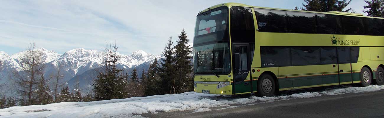 Kings Ferry Coach parked on snow lined road with alps in the background