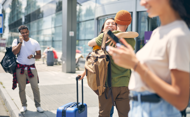 Friends outside an airport greeting each other